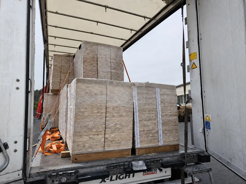 Wrapped pallets of bed-base elements strapped inside a curtain-side trailer