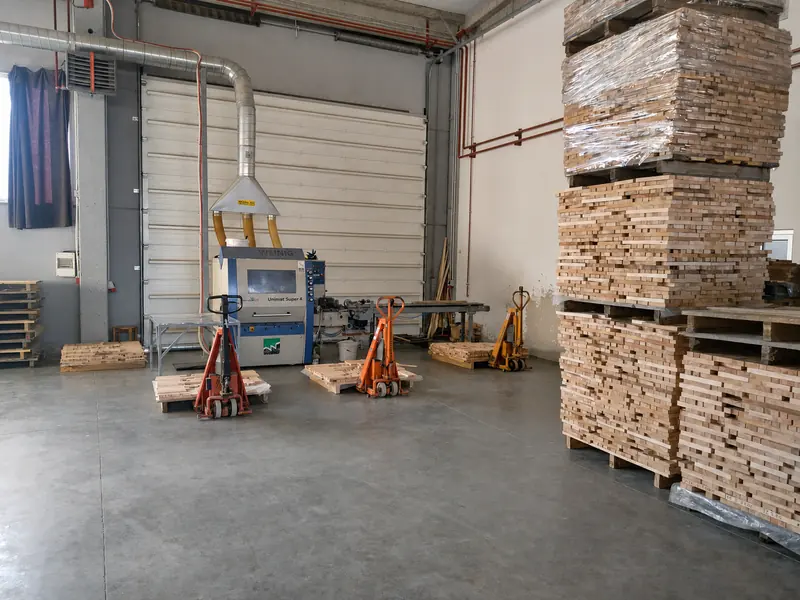 Production hall by the roller shutter door with pallet trucks and stacked short elements