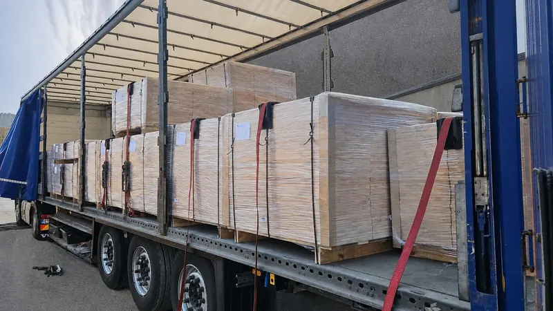 Wrapped packs of sawn elements strapped inside a curtain-side trailer