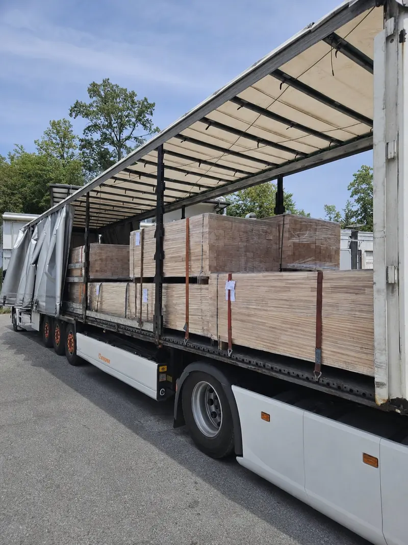 Worker checking a strapped load of edge-glued panels on a trailer