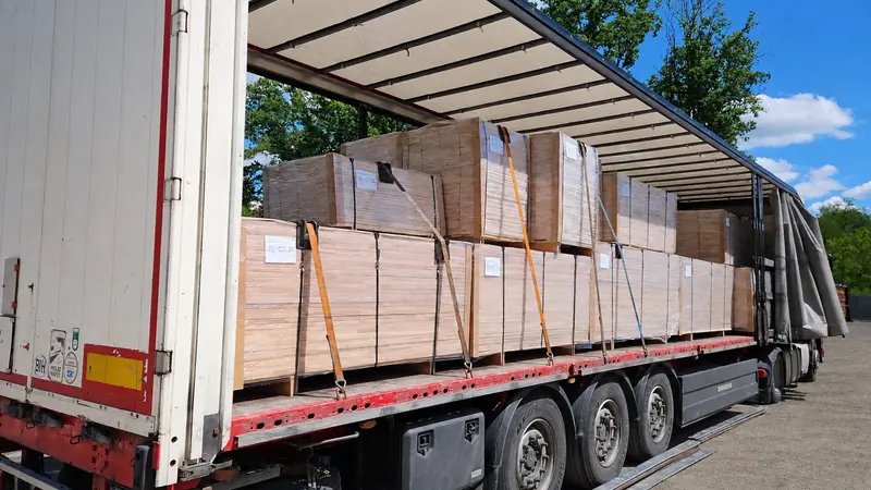 Edge-glued panels strapped and secured inside a curtain-side trailer