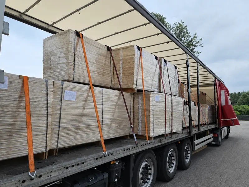 Trailer loaded with wrapped panel packs under a clear summer sky