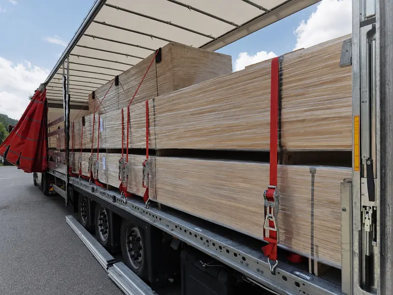 Long wrapped packs of panels secured with red straps on a trailer