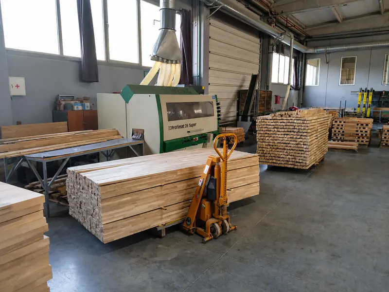 Packs of planed beech elements beside the planing machine in the hall