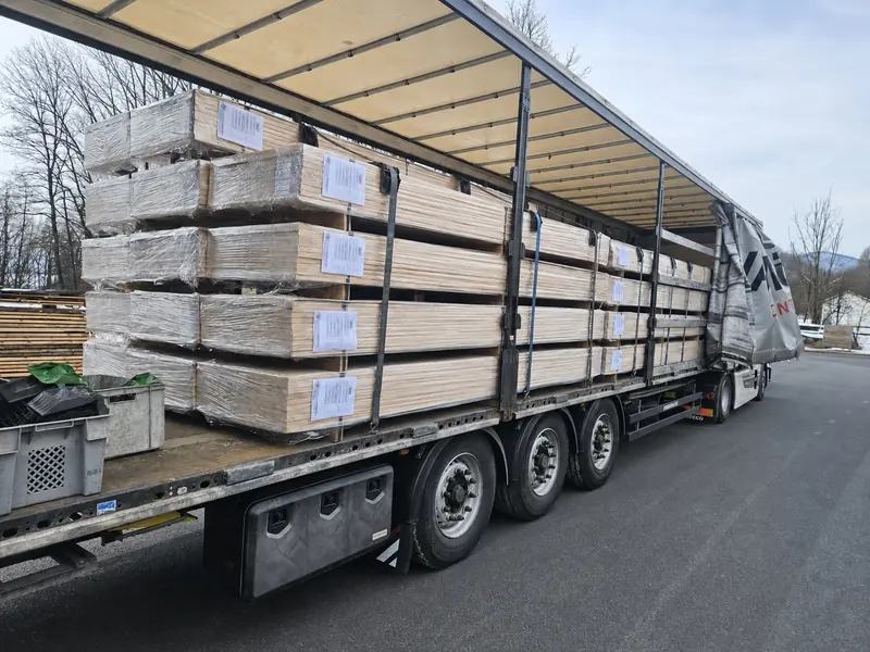 Worker loading flat wrapped packs of bed-slat elements onto a trailer in winter