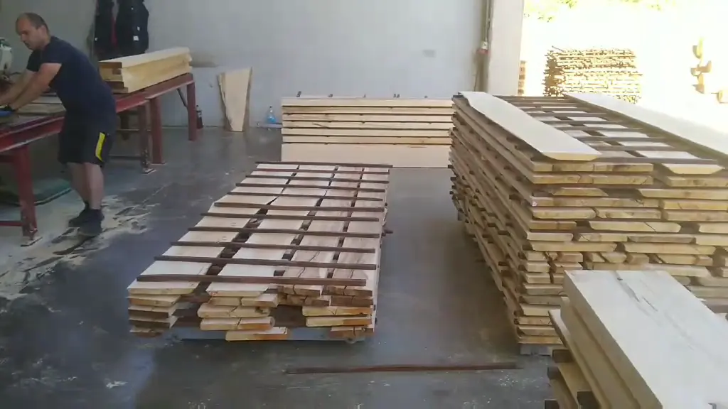 A worker beside pallets of stacked planed beech elements in the production hall